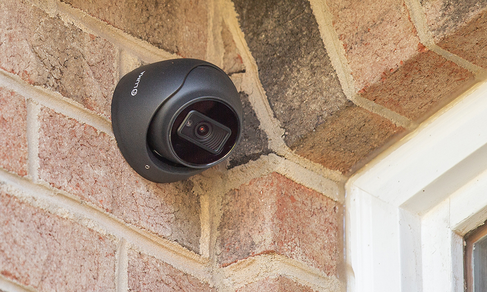 Black low-profile camera mounted on an exterior brick wall corner
